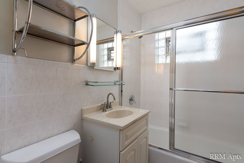 Bathroom with white tile, vanity and sliding glass shower doors, Park Avenue apartment 204